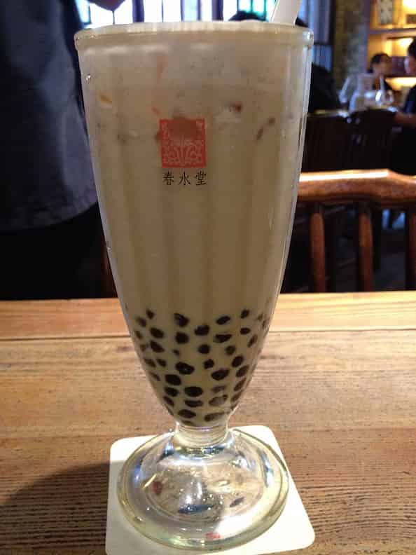 A cup of delicious bubble tea at Chun Shui Tang with bubbles floating on top and a large straw, ready to be enjoyed.