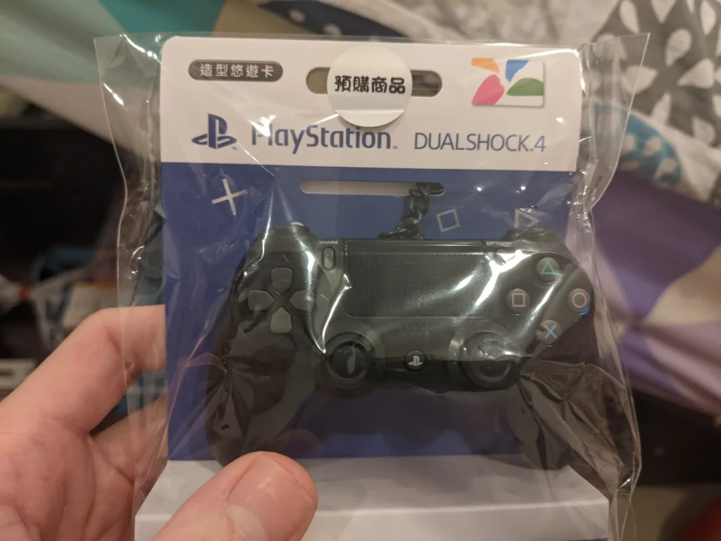 A photo of a Taipei EasyCard shaped like a Sony PlayStation DualShock controller, with green and yellow color scheme, and the EasyCard logo and information displayed on the front.